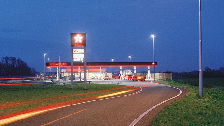 Eine in der Dämmerung attraktiv beleuchtete Texaco Tankstelle an der Autobahn - auffällige Außenbeleuchtung