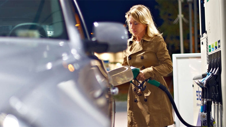 Unter einem mit Strahlern von Philips hell erleuchteten Tankstellendach betankt eine Frau ihr Auto.