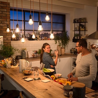 Ein Paar im Gespräch unter einer Deckenlampe mit Philips Vintage LED-Lampen, die ein gemütlich warmes Schimmern erzeugen.