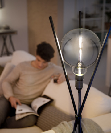 Mann, der neben einer Philips Modern LED-Lampe liest 