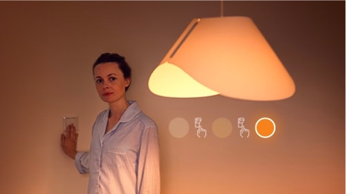 Frau schaltet die SceneSwitch Lampe auf geringe Helligkeit um.