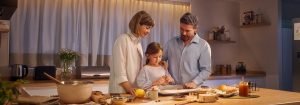 Eine Mutter und ein Vater stehen mit ihrer Tochter in einer gut beleuchteten Küche