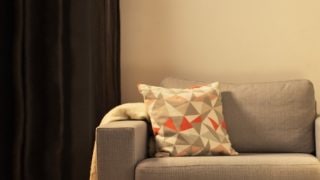 „Gemütliches Wohnzimmer mit moderner LED-Tischleuchte, die den grauen Sessel beleuchtet und ein gemütliches Licht im Haus schafft.“