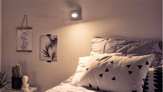 „Stilvolles Schlafzimmer mit verstellbarem LED-Spot, der ein gemütliches Licht schafft und geometrische Bettwäsche und minimalistisches Dekor beleuchtet.“